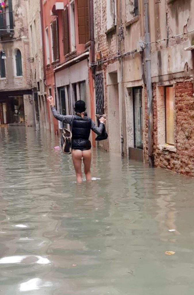ACQUA ALTA A VENEZIA, UNA DONNA CAMMINA SENZA VESTITI PER LA CALLE ALLAGATA: LA FOTO DIVENTA UN SIMBOLO
